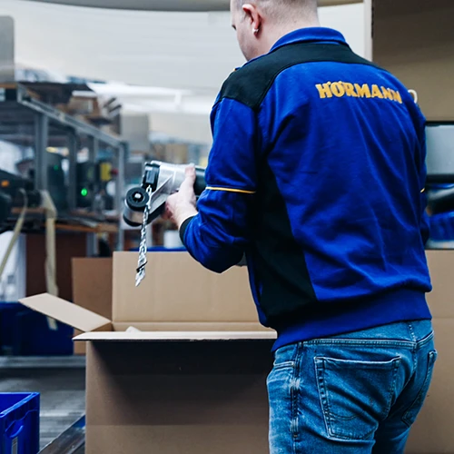 Sprick Insights: Hörmann automatisiert Verpackung 13 Antrieb und Kartonage erreichen den Packplatz. Der Mitarbeiter muss lediglich das Produkt im Karton platzieren.